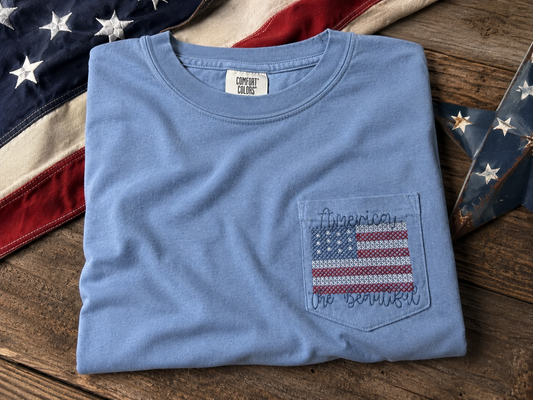 Folded blue t-shirt with American flag design embroidered.