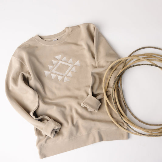 Beige sweatshirt with geometric design and coiled beige rope on a white background