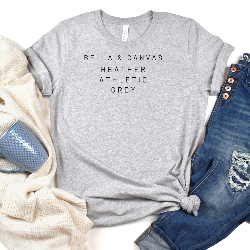 Gray t-shirt with 'Bella & Canvas' text, surrounded by denim jeans and a beige sweater on a white background