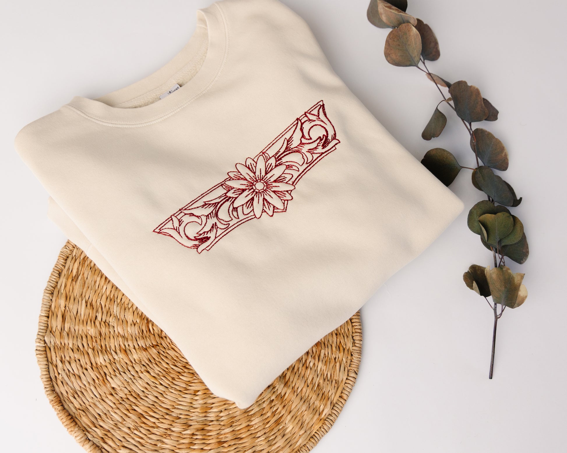 Beige sweatshirt with red floral design on a white background