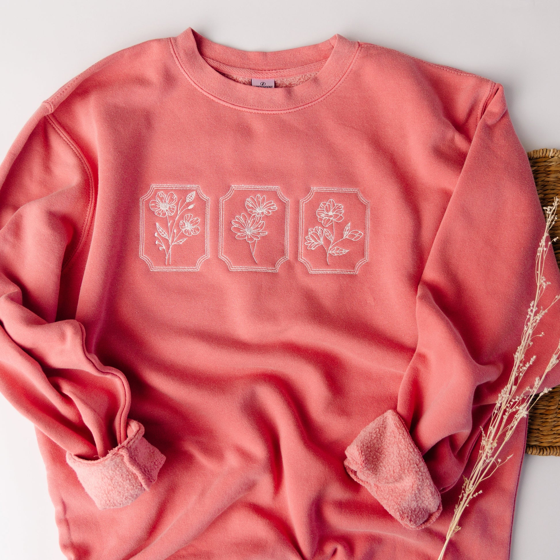 Pink sweatshirt with floral designs on a light gray background