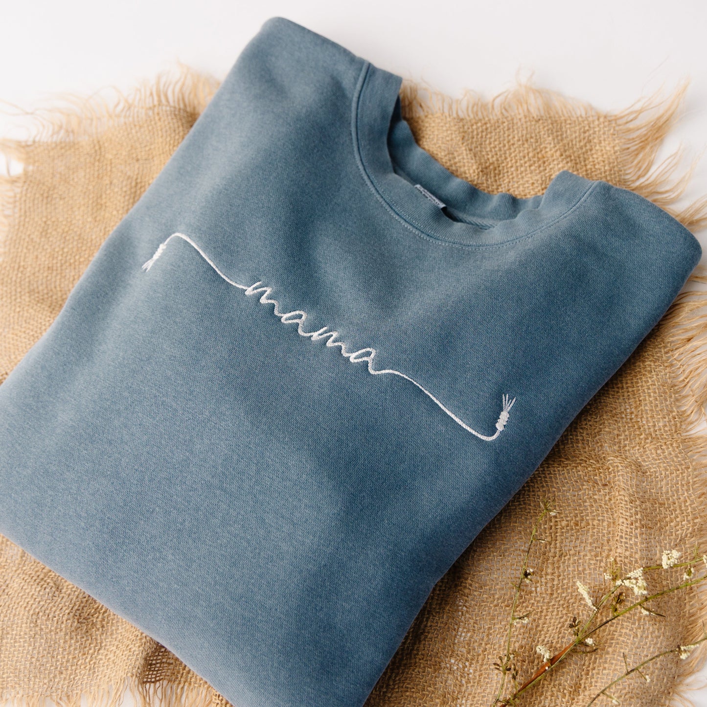 Blue sweatshirt with 'mama' embroidery on a textured surface