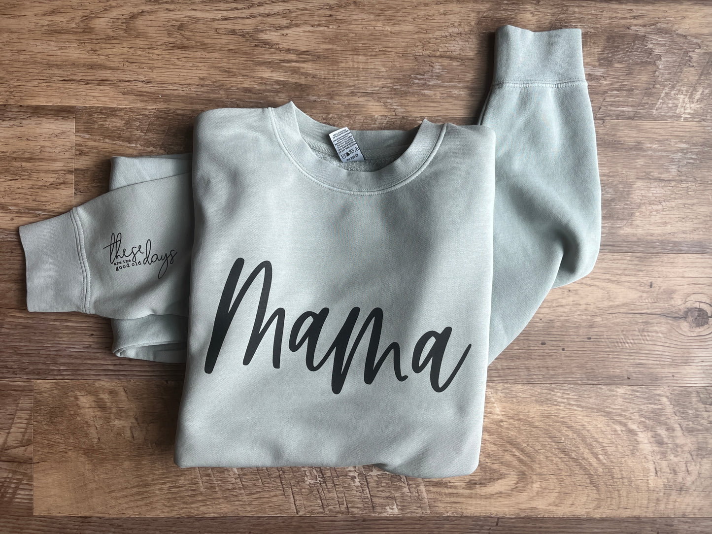 Gray sweatshirt with 'mama' text on a wooden surface