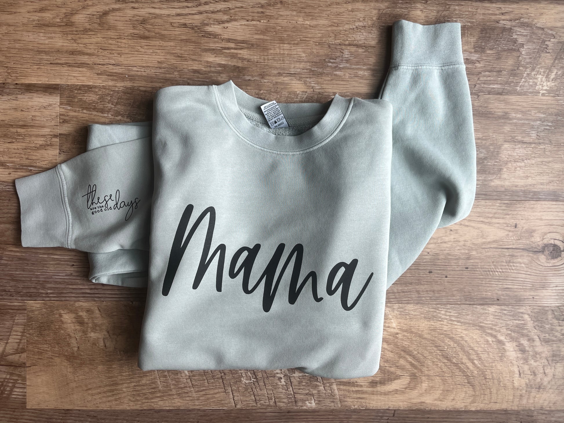 Gray sweatshirt with 'mama' text on a wooden surface