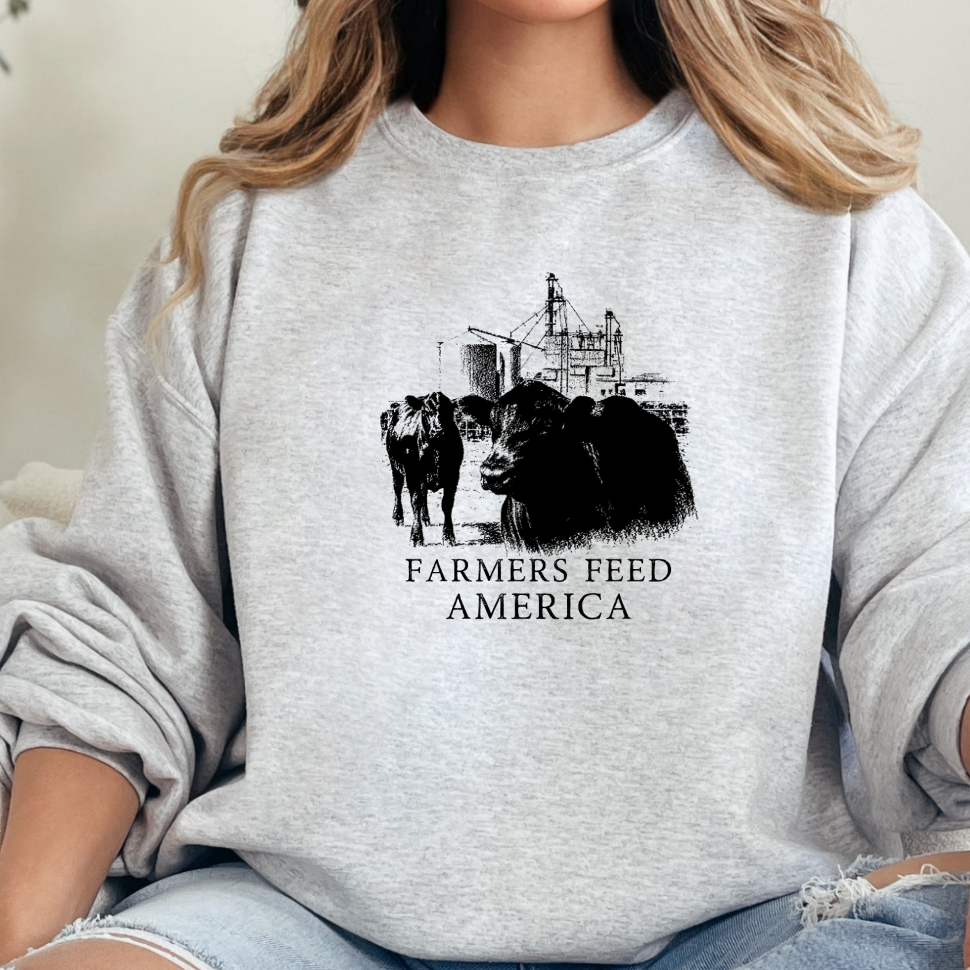 Person wearing a gray sweatshirt with a graphic of cows and the text 'Farmers Feed America'.