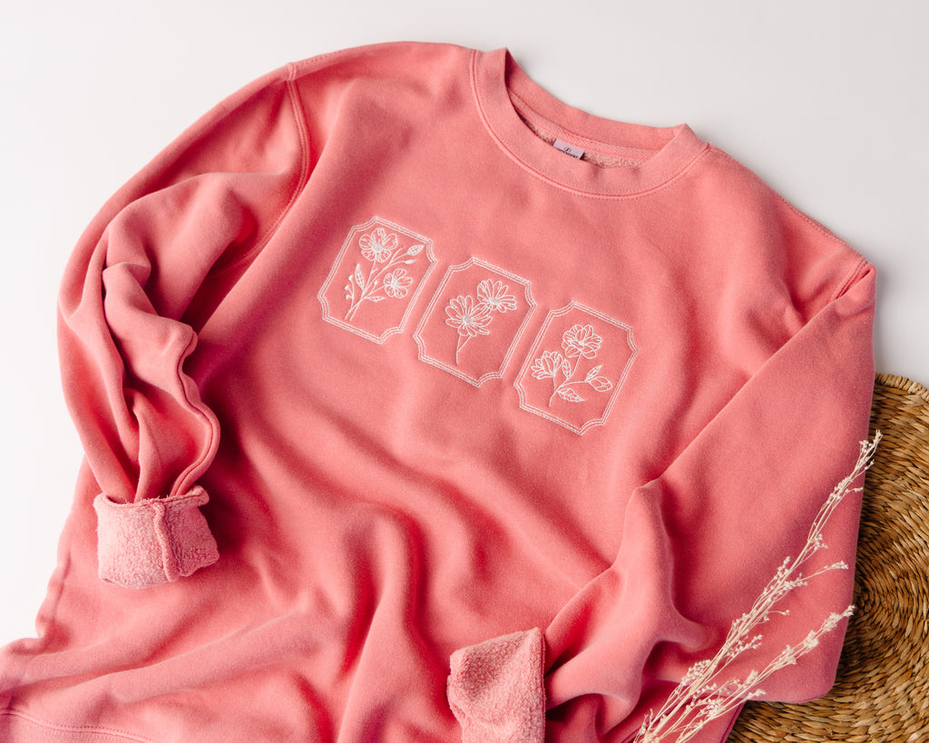 Pink sweatshirt with floral designs on a light background