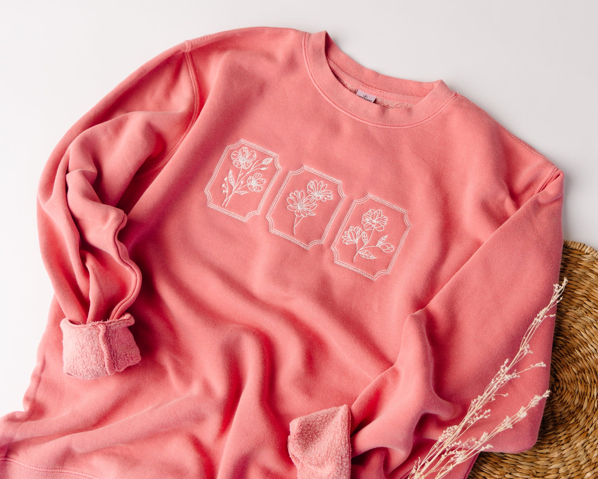 Pink sweatshirt with floral designs on a light background