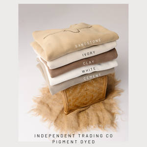 Stack of folded fabric swatches in various neutral colors with color names on a light gray background.