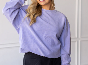 Person wearing a light purple sweater against a white wall