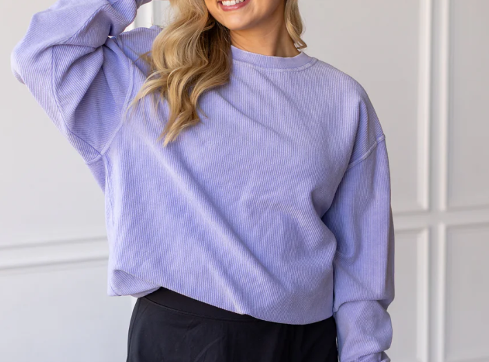 Person wearing a light purple sweater against a white wall