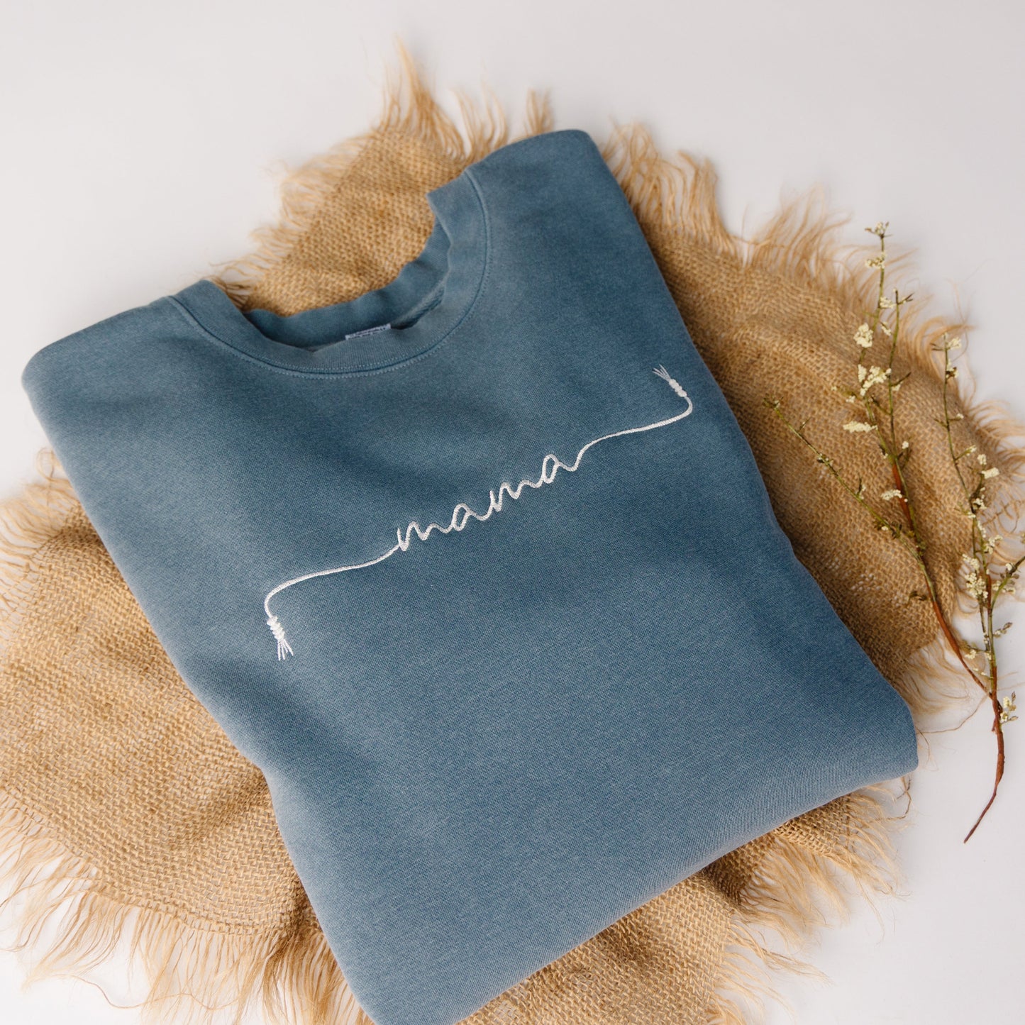 Blue sweatshirt with 'mama' embroidery on a textured surface