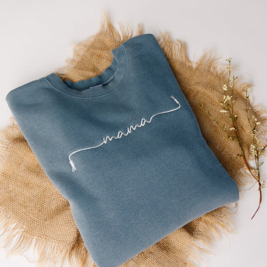 Blue sweatshirt with 'mama' embroidery on a textured surface
