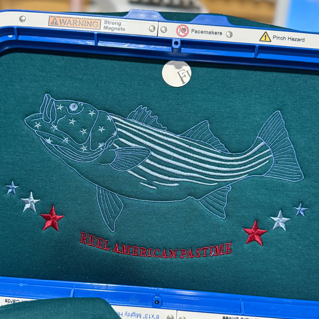 Embroidery design of a fish with stars on a green surface, featuring text ' reel American Pastime'.