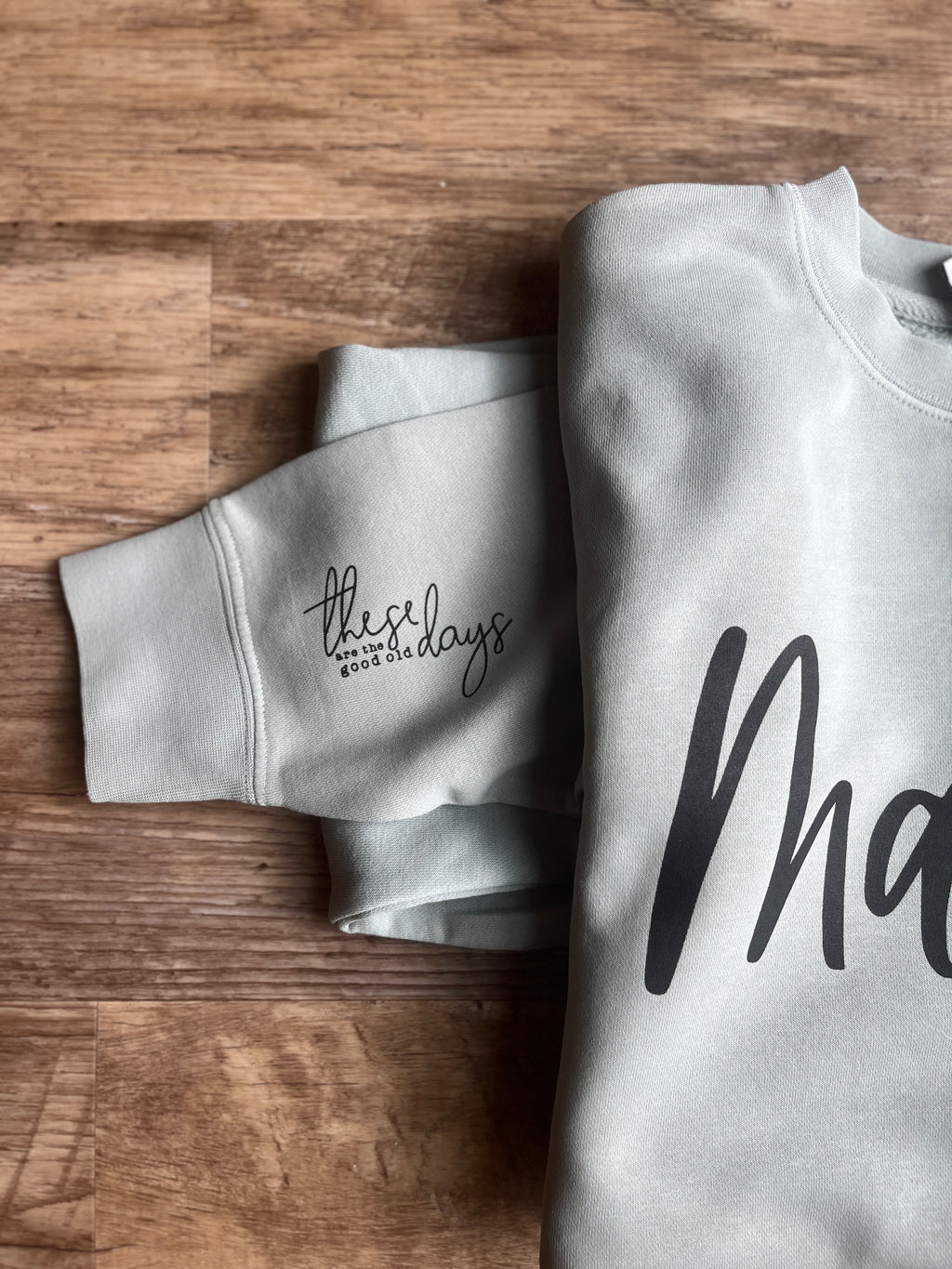 one gray mama sweatshirt with text on a wooden surface