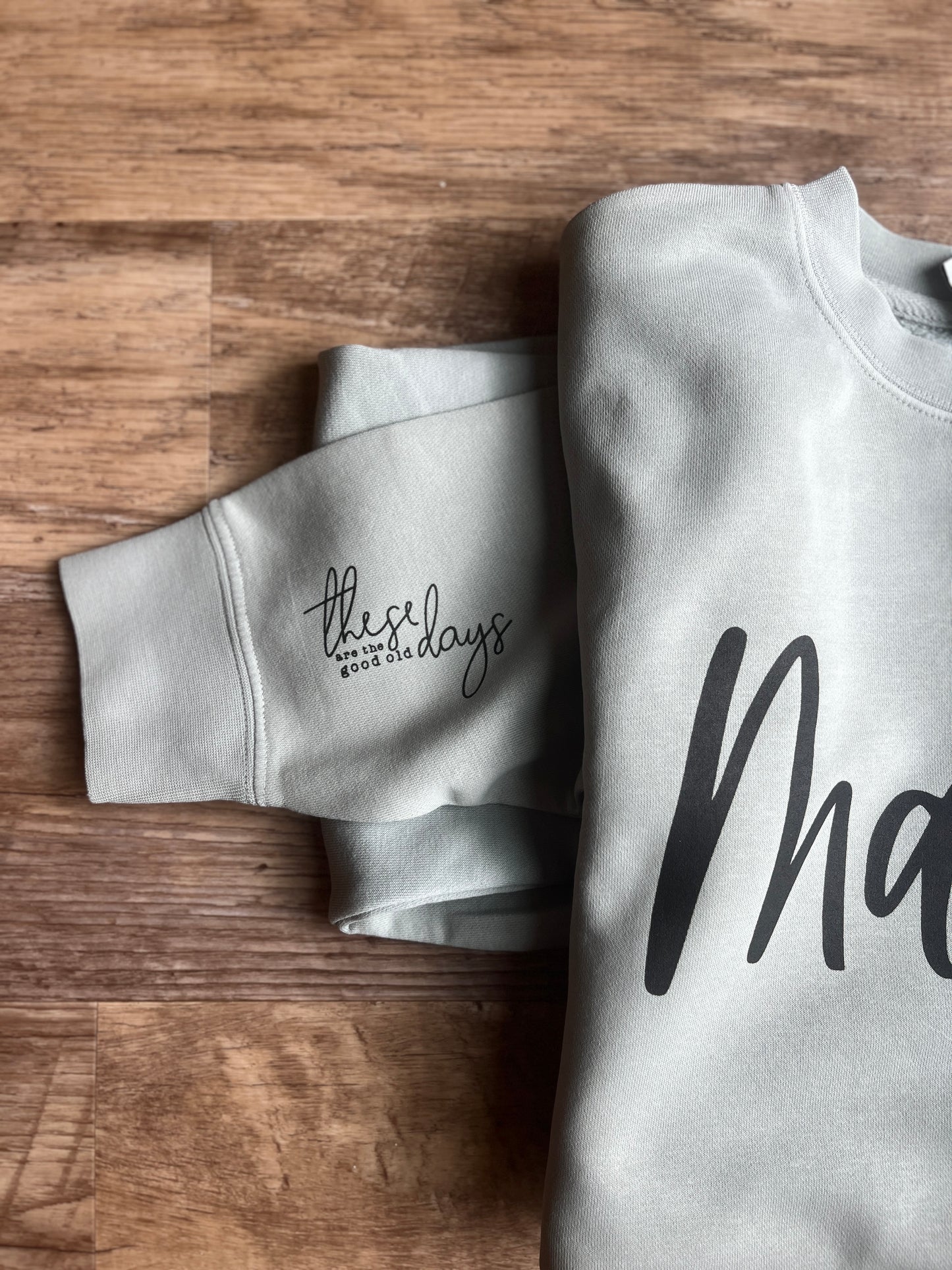 one gray mama sweatshirt with text on a wooden surface