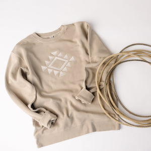 Beige sweatshirt with geometric design and coiled beige rope on a white background