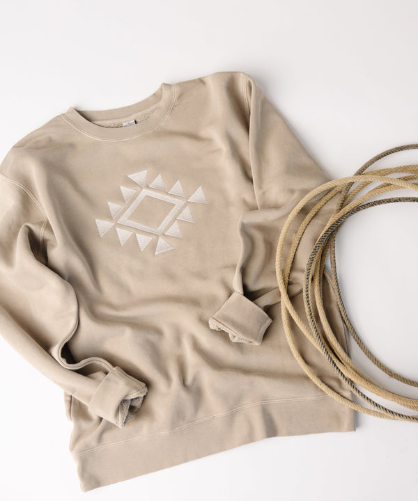 Beige sweatshirt with geometric design and coiled beige rope on a white background