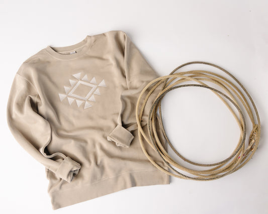 Beige sweatshirt with geometric design and coiled beige rope on a white background