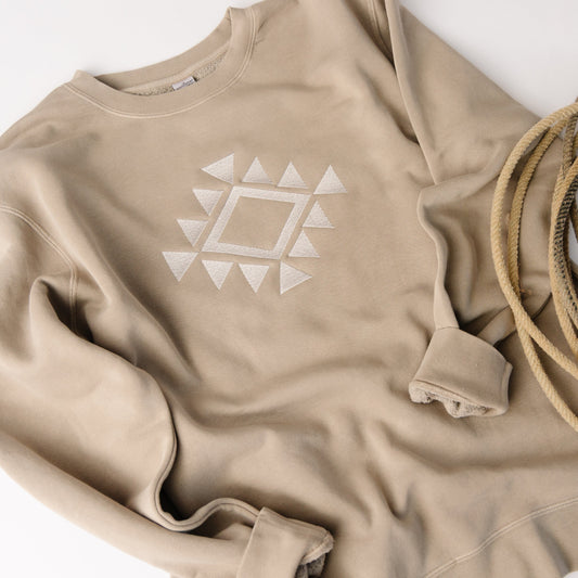 Beige sweatshirt with geometric design and coiled beige rope on a white background
