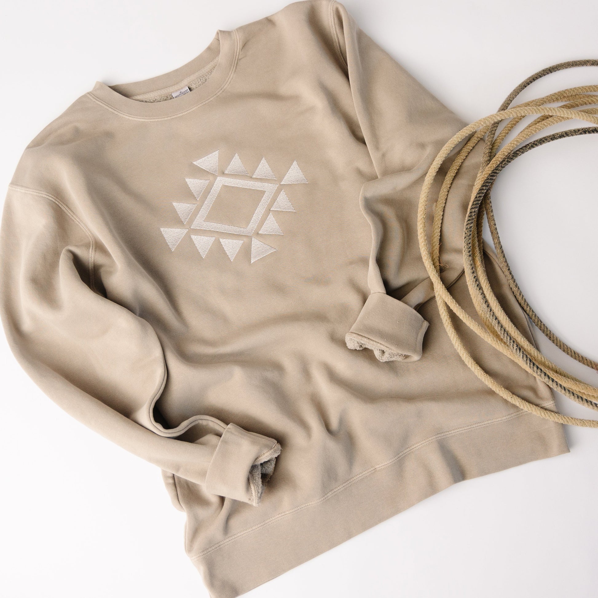 Beige sweatshirt with a white geometric design on a white background