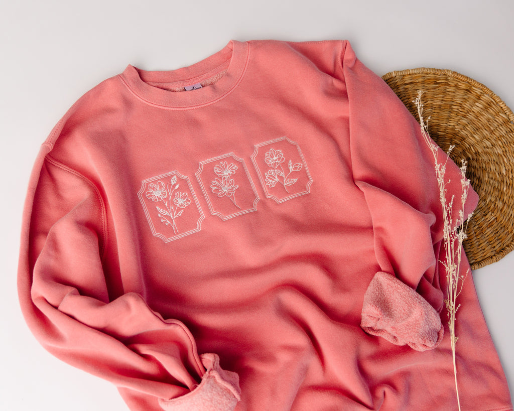Pink sweatshirt with floral designs on a light gray background