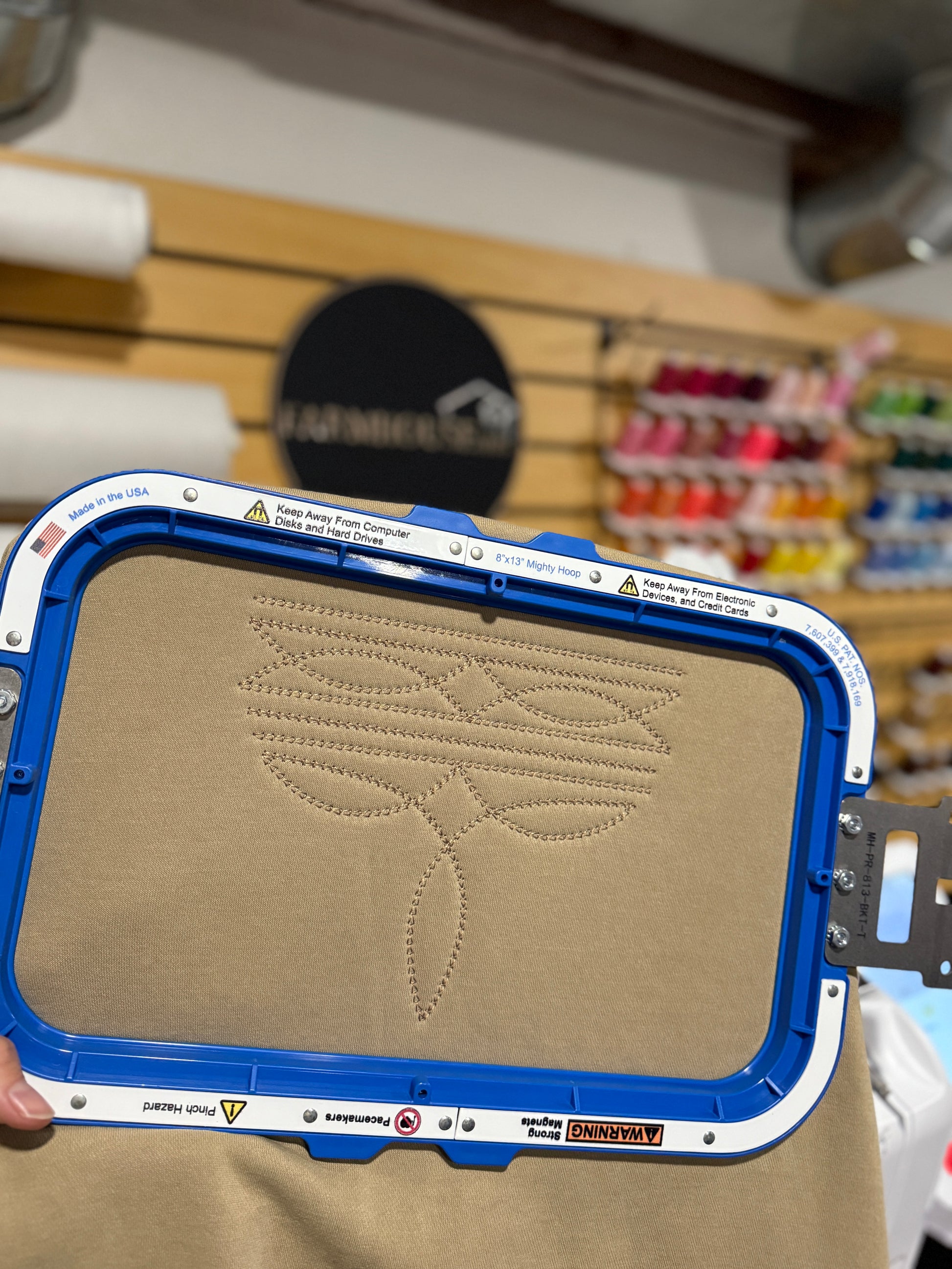 Embroidery machine hoop with a western design on fabric against a blurred store background