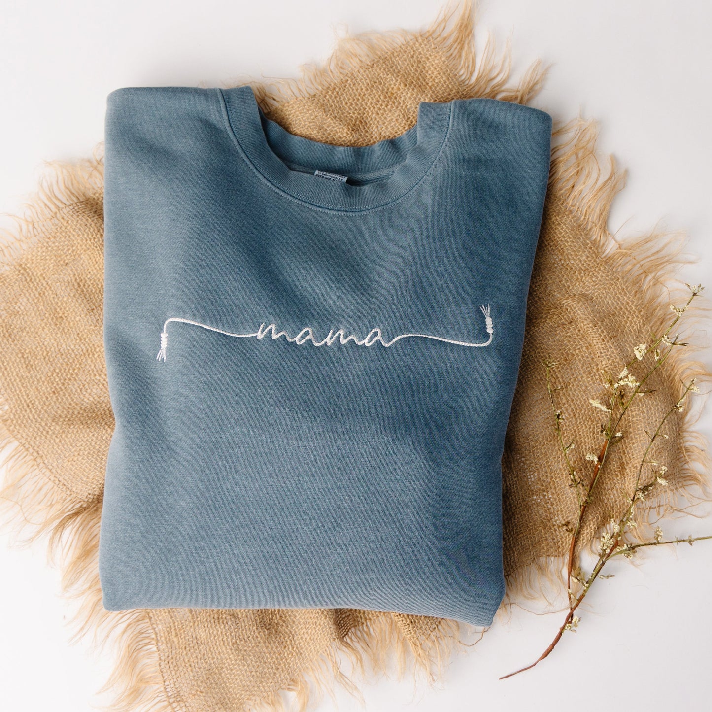 Blue sweatshirt with 'mama' embroidery on a textured surface
