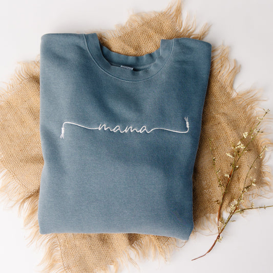Blue sweatshirt with 'mama' embroidery on a textured surface