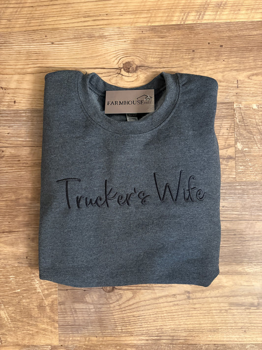 A gray crewneck sweatshirt with the text 'Farmerish' embroidered on the front, displayed on a wooden hanger against a rustic background.