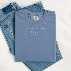 Folded blue shirt with 'Comfort Colors Blue Jean' text on a white background