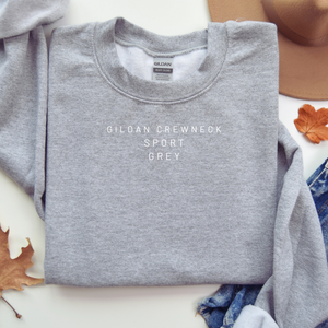 Folded gray Gildan sweatshirt with visible brand label on a white surface.