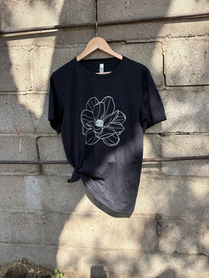 Black t-shirt with a white floral design on a stone surface