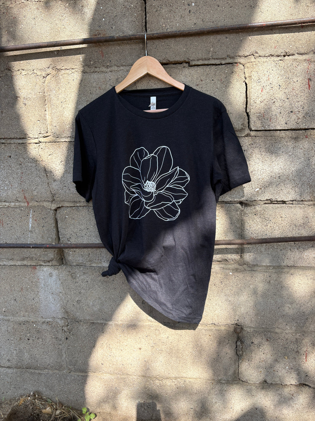 Black t-shirt with a white floral design on a stone surface
